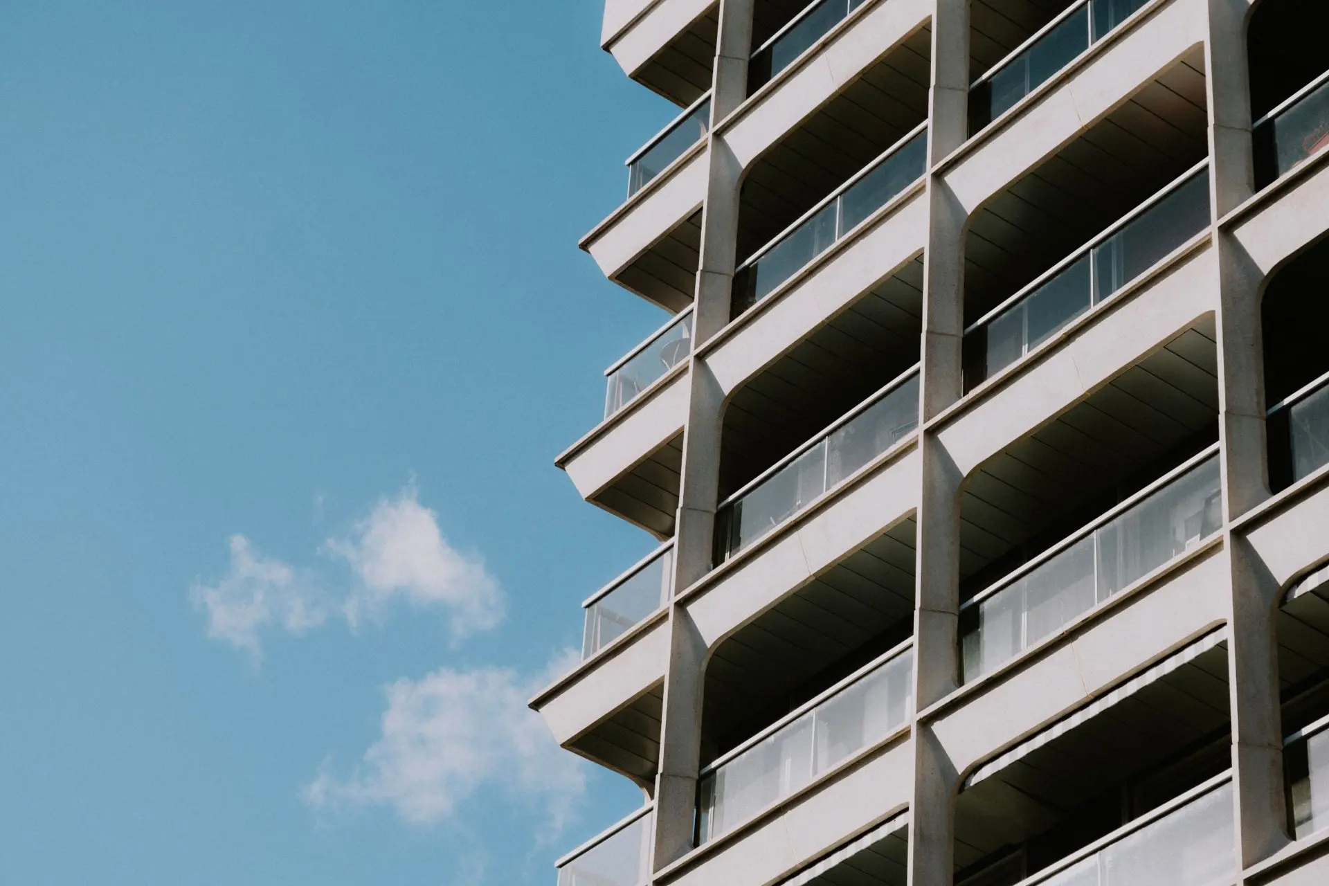 Fassade einer Wohnliegenschaft mit Balkonen vor blauem Himmel